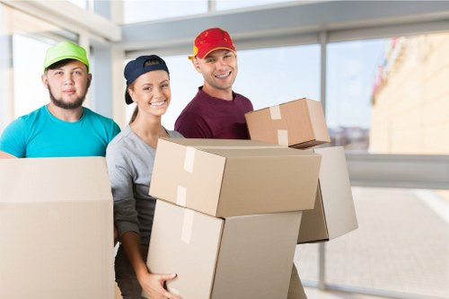 Local movers carrying household items through a West Ham property entrance